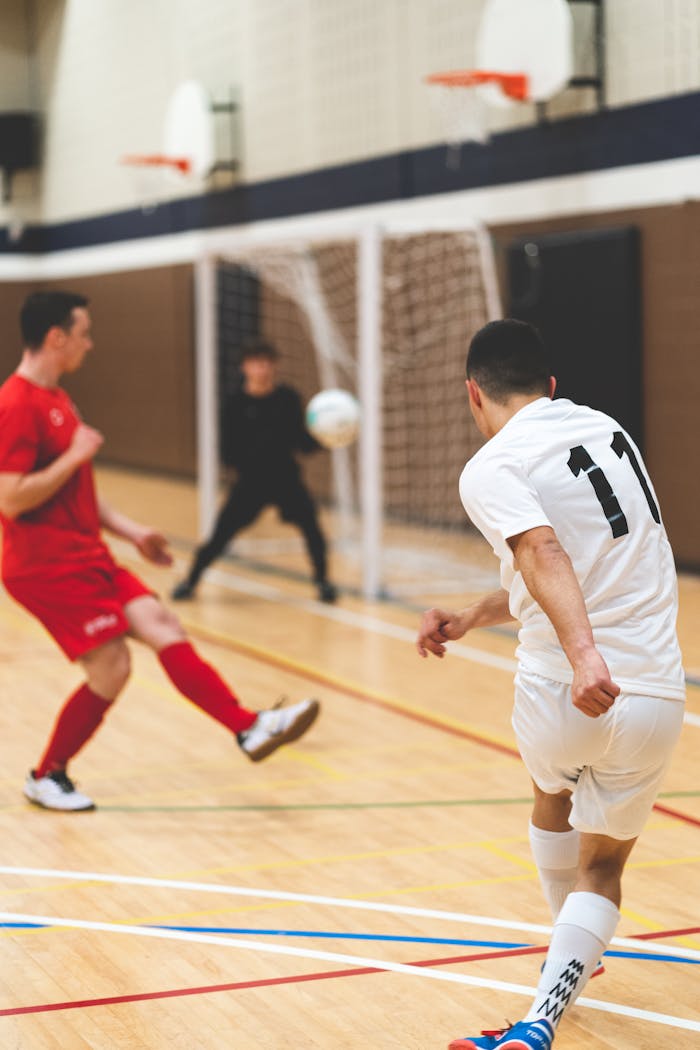 Action shot of an indoor soccer game with players in motion near the goal.