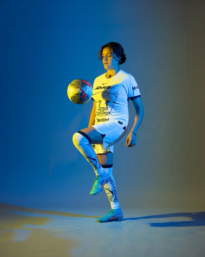 Dynamic shot of a female soccer player balancing a ball in a vibrant studio